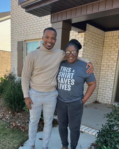 Teré with a smiling buyer outside her new home