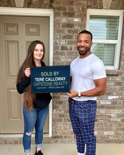 Teré with a buyer holding a Sold by Teré Calloway sign at her front door
