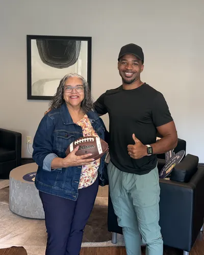 Teré with a buyer holding a signed football, her closing gift