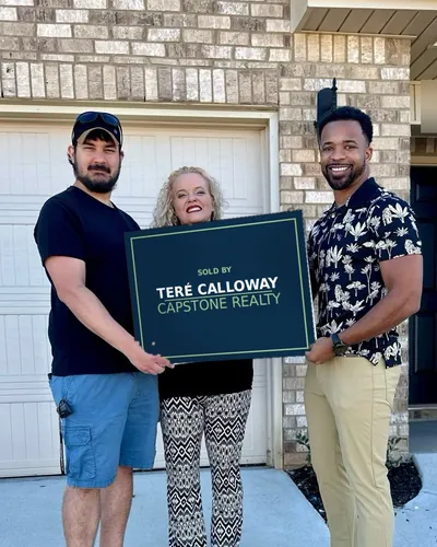 Teré with two buyers holding a Sold by Teré Calloway sign in the driveway