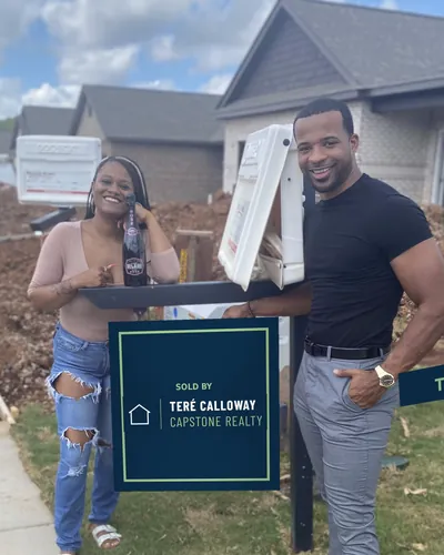 Teré with a buyer beside the Sold by Teré Calloway sign at her new build